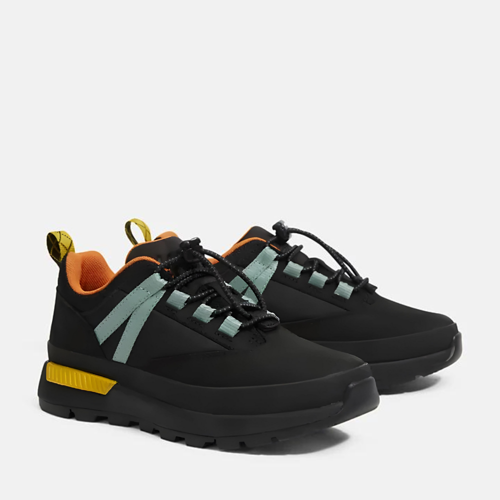 Timberland® Euro Trekker Low Lace Up Sneaker for Junior. Black sneaker with green accents, featuring a lace-up closure for a secure fit, comfortable footbed, and lugged outsole for traction on various terrains. Made with partly recycled materials. Perfect for outdoor activities.