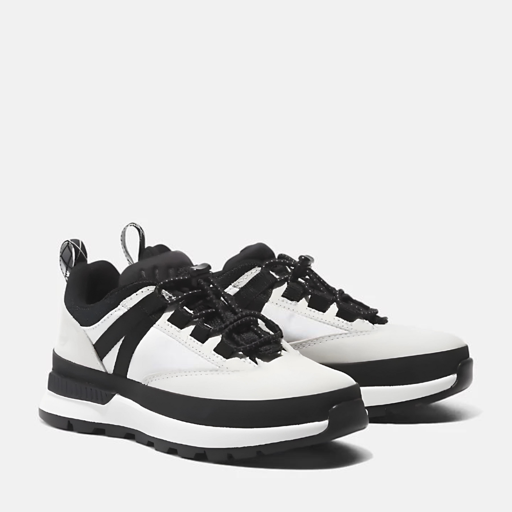 Timberland® Euro Trekker Low Lace Up Sneaker for Junior. Black and white sneaker featuring a lace-up closure for a secure fit, comfortable footbed, and lugged outsole for traction. Made with partly recycled materials. Pairs well with various outfits for everyday wear or light adventures.