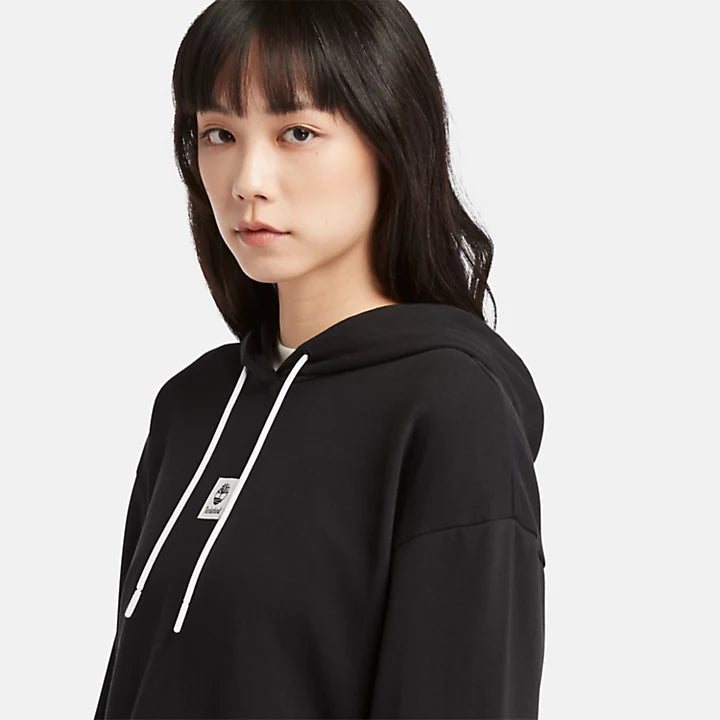 Black Timberland® Women's Loopback Hoodie. Made with 80% cotton for softness and breathability. Dropped-shoulder silhouette for a relaxed, modern look. Drawcord-adjustable hood for warmth and coverage