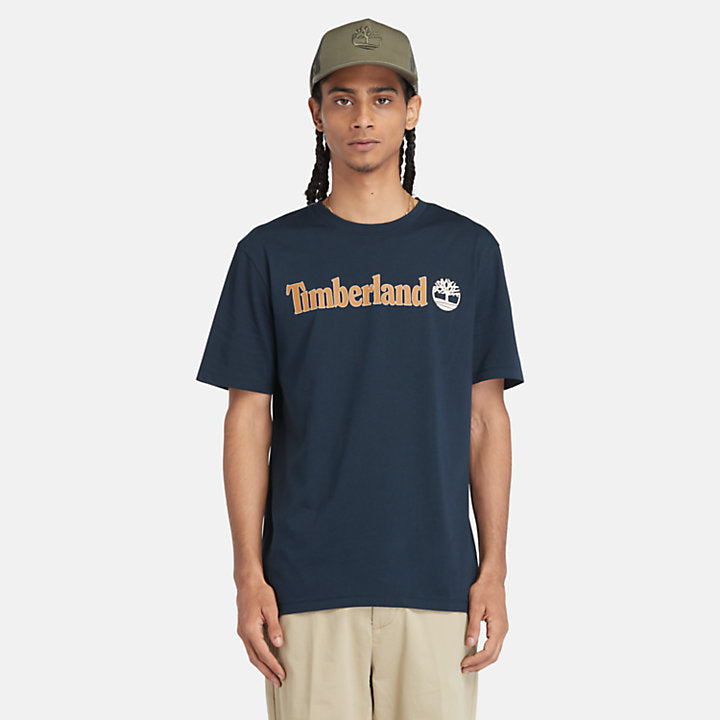 Navy Timberland® Kennebec River Linear Logo Tee. 100% cotton for softness and breathability. Crew neck, relaxed fit, short sleeves. Logo print for heritage style. Pairs well with casual pants.