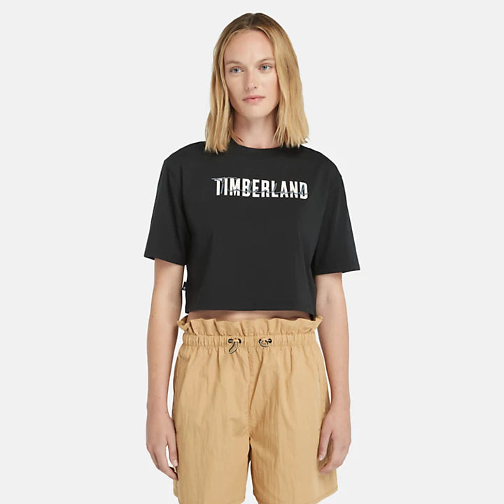 Black Timberland® Cropped Short Sleeve Tee for Women. Soft, breathable 100% cotton. Relaxed fit for comfort. Cropped silhouette for a trendy look. Ribbed collar for a snug fit. Iridescent graphic print for eye-catching style.