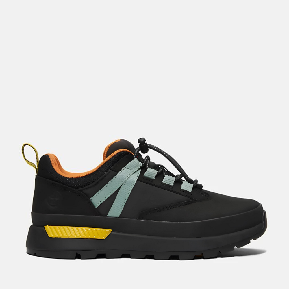 Timberland® Euro Trekker Low Lace Up Sneaker for Junior. Black sneaker with green accents, featuring a lace-up closure for a secure fit, comfortable footbed, and lugged outsole for traction on various terrains. Made with partly recycled materials. Perfect for outdoor activities.