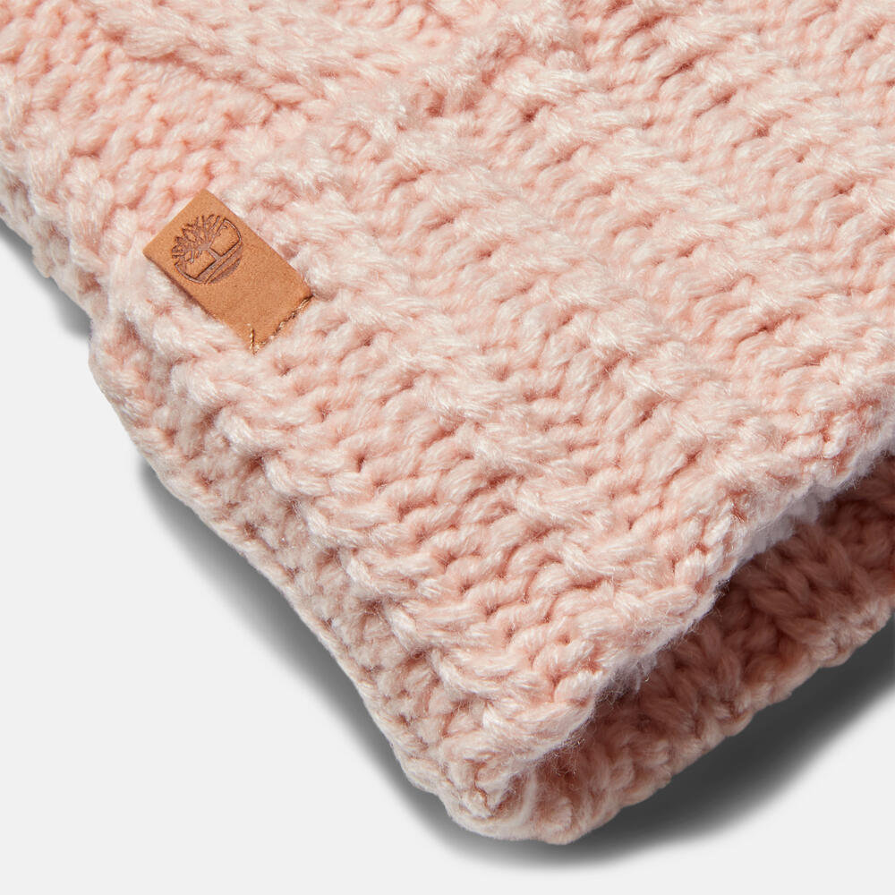 Rose Timberland Cable Knit Pom Pom Beanie for Women. Soft and chunky cable knit for warmth and texture. Fold-over cuff for adjustability. Fluffy pom pom for a playful touch. Rose colour for femininity.