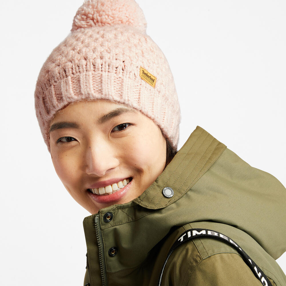 Rose Timberland® Cable Knit Pom Pom Beanie for Women. Soft and chunky cable knit for warmth and texture. Fold-over cuff for adjustability. Fluffy pom pom for a playful touch. Rose colour for femininity.