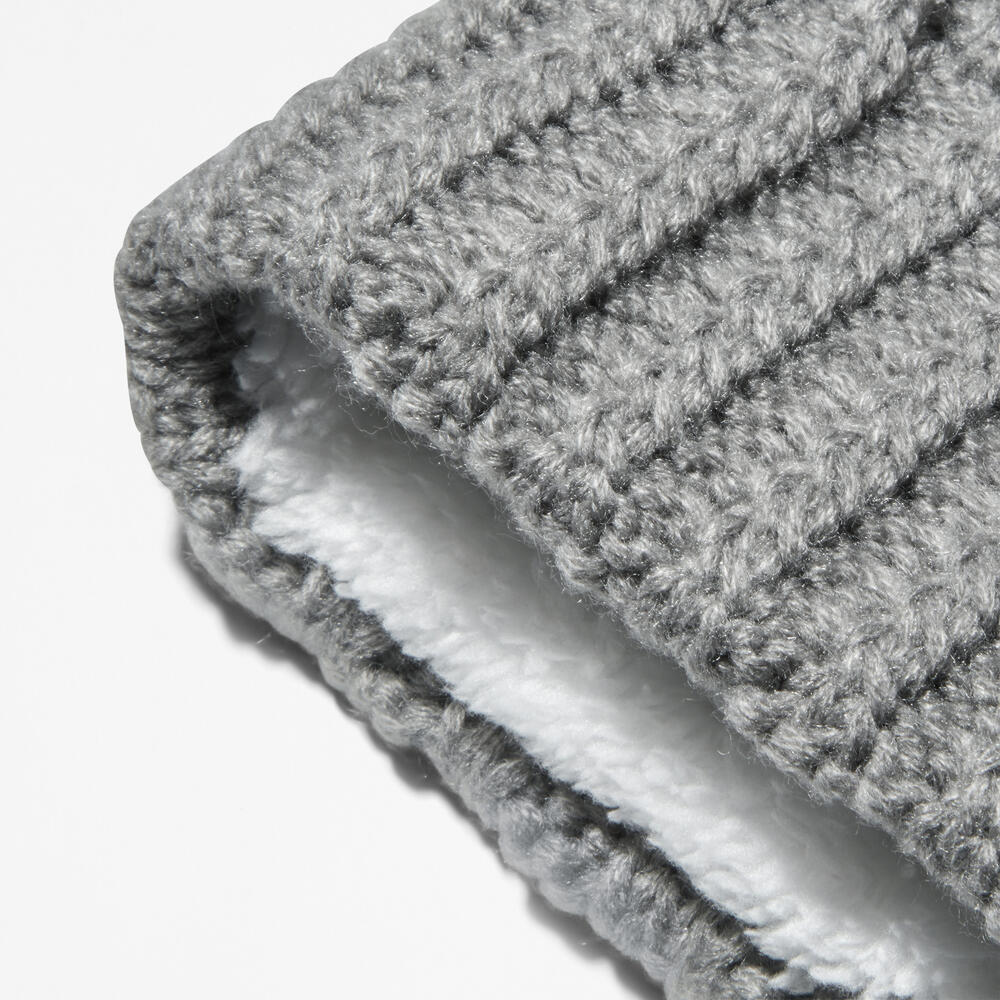 Grey Timberland® Cable Knit Pom Pom Beanie for Women. Soft and chunky cable knit for warmth and texture. Fold-over cuff for adjustability. Fluffy pom pom for a playful touch. Grey color for versatility.