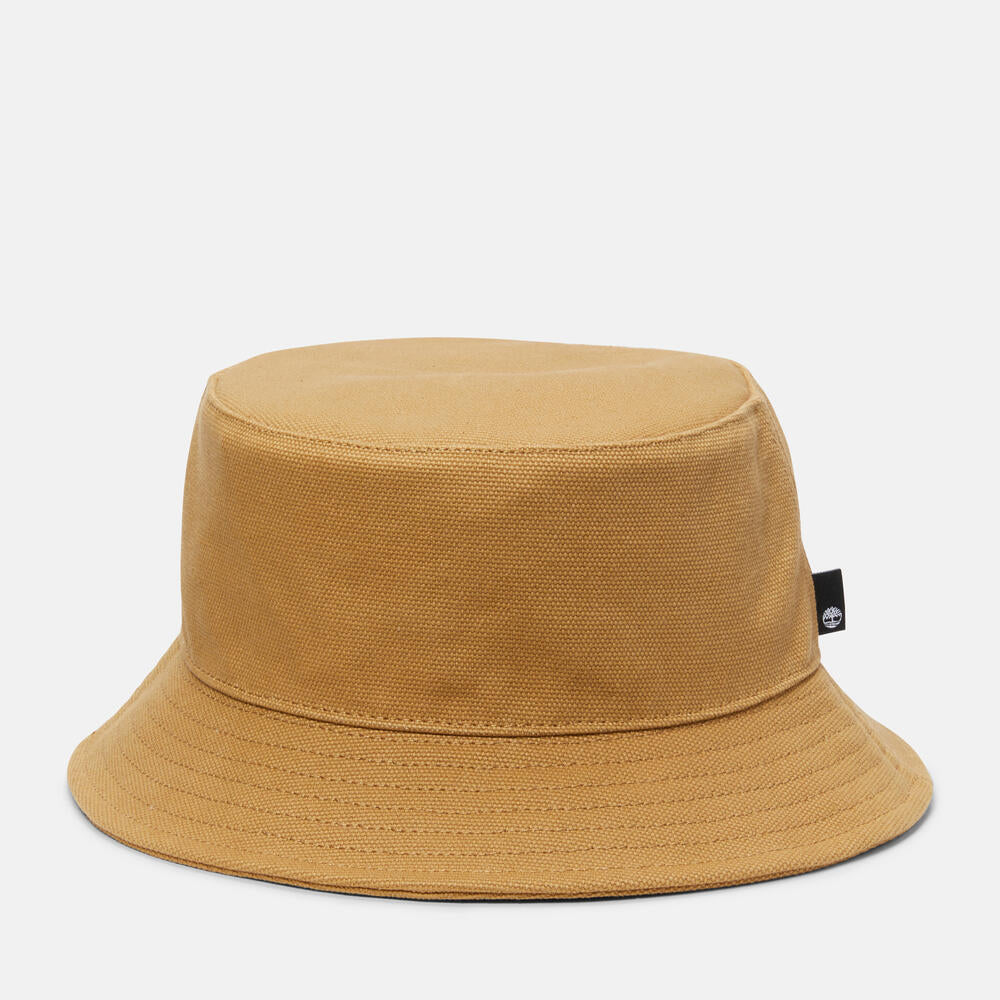 Timberland® Icons of Desire Bucket Hat for Men in Wheat. Classic bucket hat made from 100% cotton for a comfortable and breathable fit. Unstructured design for a relaxed look. Wide brim for sun protection. Wheat color with contrasting dark orange stitch on the sweatband. Anti-microbial treatment for odor control. Versatile and perfect for everyday wear.