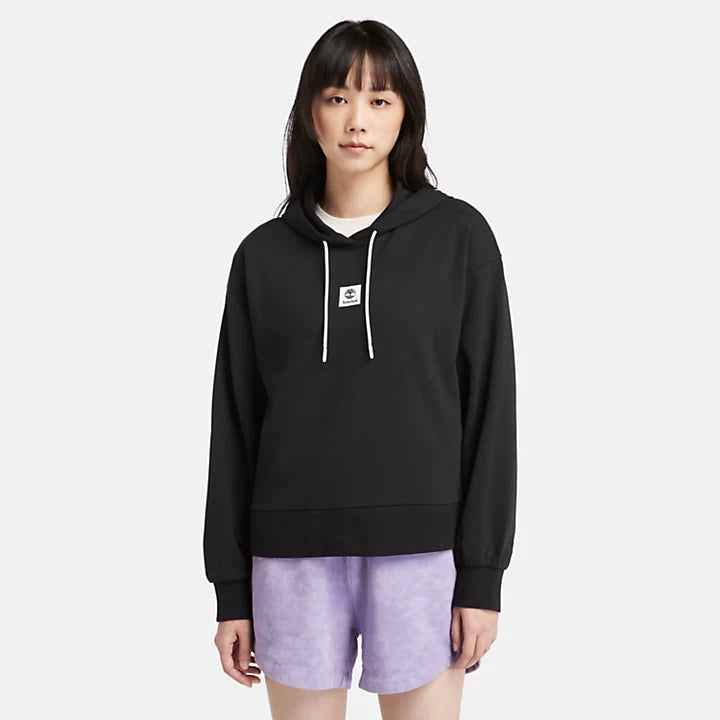 Black Timberland® Women's Loopback Hoodie. Made with 80% cotton for softness and breathability. Dropped-shoulder silhouette for a relaxed, modern look. Drawcord-adjustable hood for warmth and coverage