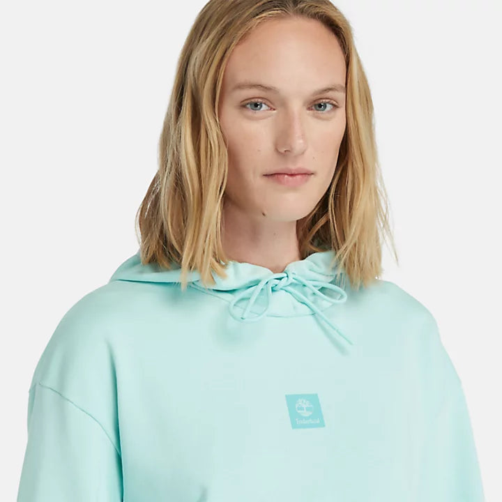 Light blue Timberland Women's Loopback Hoodie. Made with 80% cotton for softness and breathability. Dropped-shoulder silhouette for a relaxed look. Drawcord-adjustable hood for warmth and coverage.