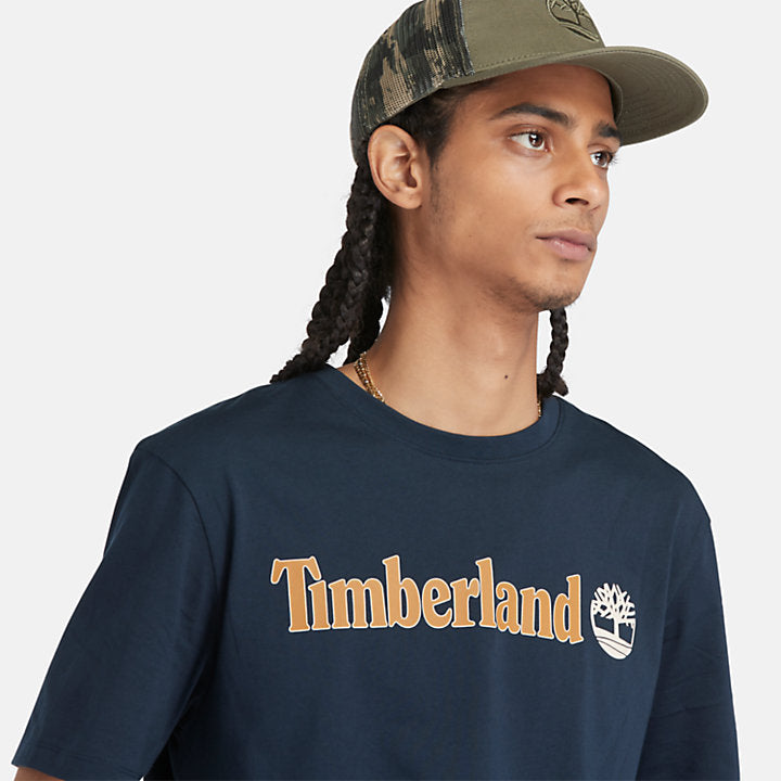 Navy Timberland® Kennebec River Linear Logo Tee. 100% cotton for softness and breathability. Crew neck, relaxed fit, short sleeves. Logo print for heritage style. Pairs well with casual pants.