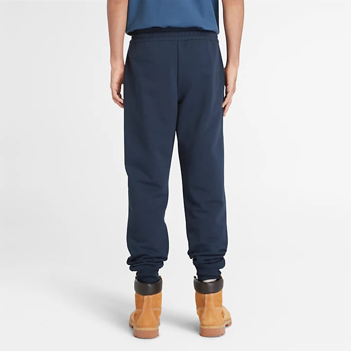 Timberland® Loopback Sweatpants for Men. Grey sweatpants featuring a relaxed fit with a mid-rise, tapered leg, and ribbed ankle cuffs. Made from a soft knit fabric with 82% cotton and 18% polyester (including 82% organically grown cotton).  Includes handy side pockets, an elasticated drawcord waistband, and an embroidered logo for a touch of style. Perfect for everyday wear.