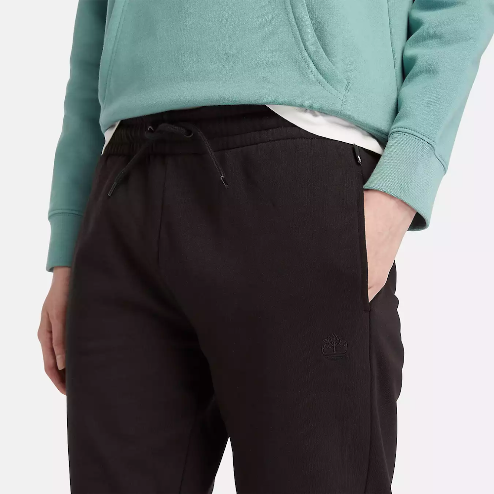 Black Timberland Brushed Back Joggers for Women. Black sweatpants featuring a soft, brushed-back fabric for warmth and comfort.  These joggers offer a relaxed fit with an elasticated drawstring waistband, cuffed ankles, and two handy side pockets