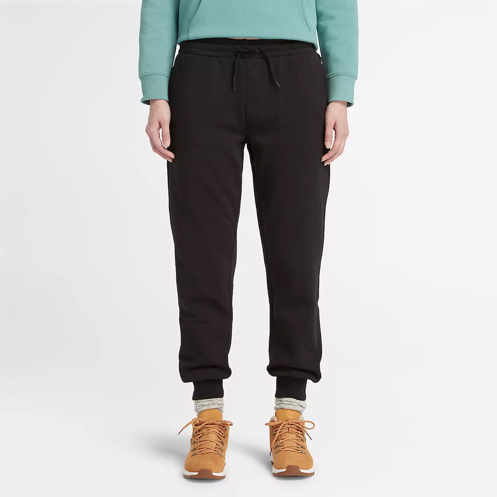 Black Timberland Brushed Back Joggers for Women. Black sweatpants featuring a soft, brushed-back fabric for warmth and comfort.  These joggers offer a relaxed fit with an elasticated drawstring waistband, cuffed ankles, and two handy side pockets