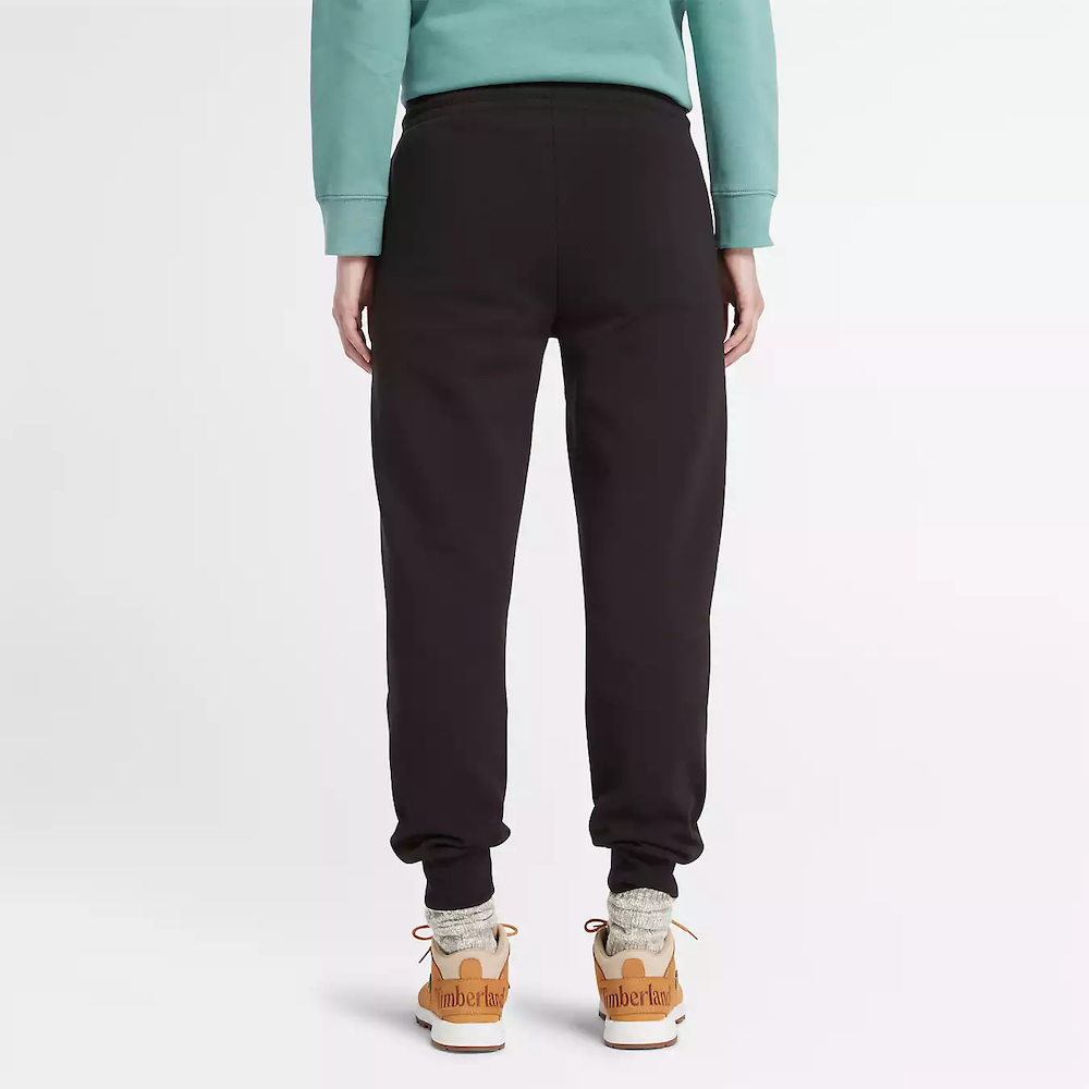Black Timberland Brushed Back Joggers for Women. Black sweatpants featuring a soft, brushed-back fabric for warmth and comfort.  These joggers offer a relaxed fit with an elasticated drawstring waistband, cuffed ankles, and two handy side pockets